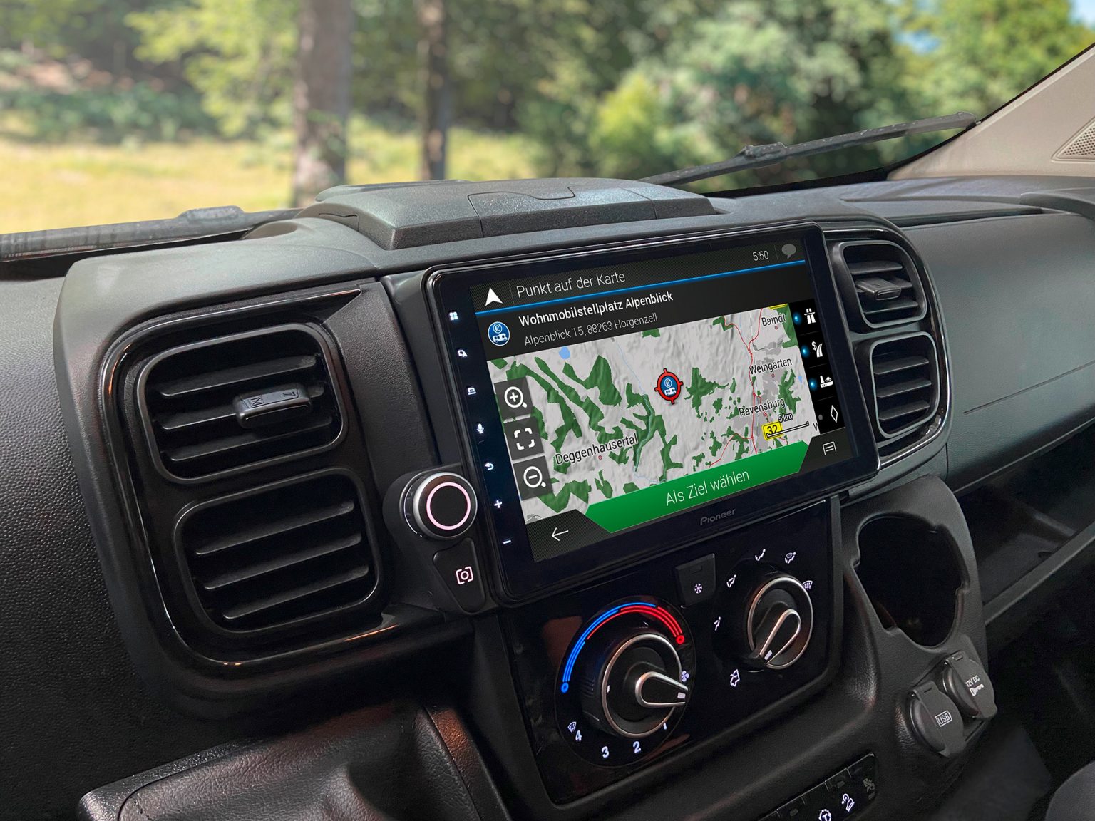 Schräg von der linken Seite fotografiertes Armaturenbrett eines Fiat Ducato mit eingebautem Pioneer Mediacenter AVIC-Z1000DAB. Durch die Windschutzsscheibe ist ein Wald zu sehen. Der Bildschirm des AVIC-Z1000DAB zeigt eine Navigations-Ansicht.