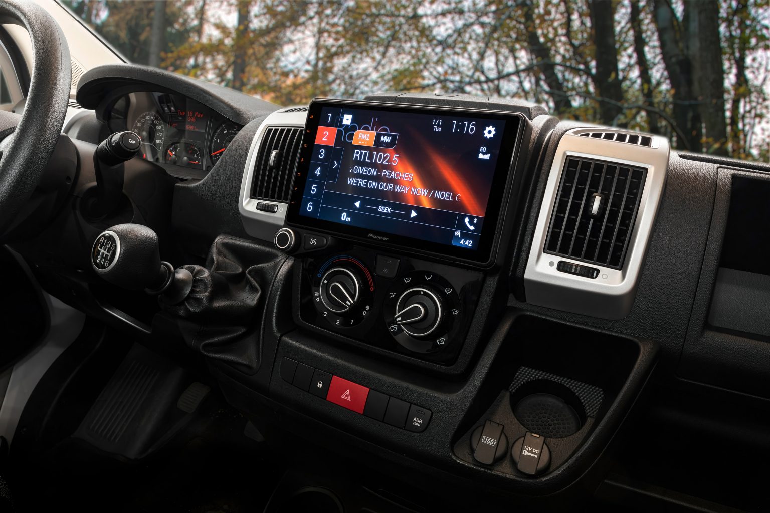 Schräg von der rechten Seite fotografiertes Armaturenbrett eines Fiat Ducato mit eingebautem Pioneer Mediacenter AVIC-Z1000DAB. Durch die Windschutzsscheibe ist ein Wald zu sehen. Der Bildschirm des AVIC-Z1000DAB zeigt eine Mediaplayer-Ansicht.